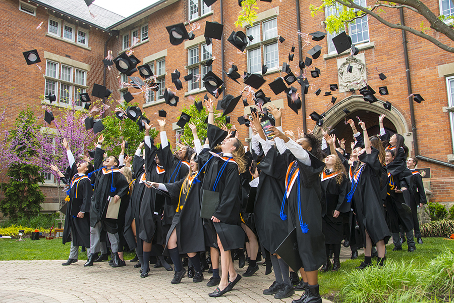 photo of students throwing their mortarboard hats into the air